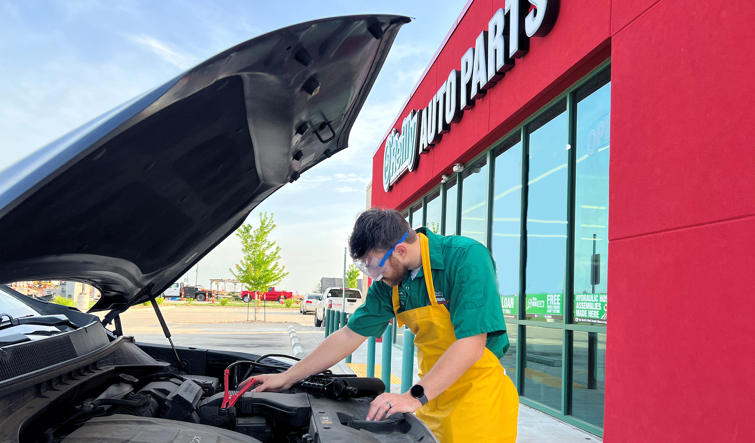 An O'Reilly team member provides a free battery check on a customer's car.