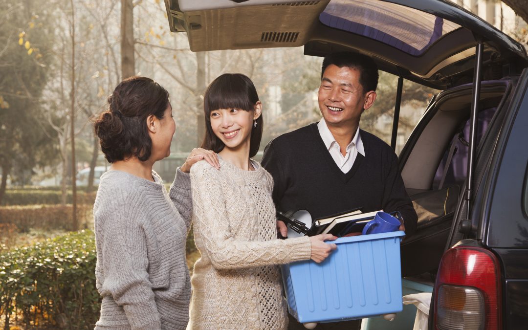 A mother and father help their daughter pack the car to go to college.