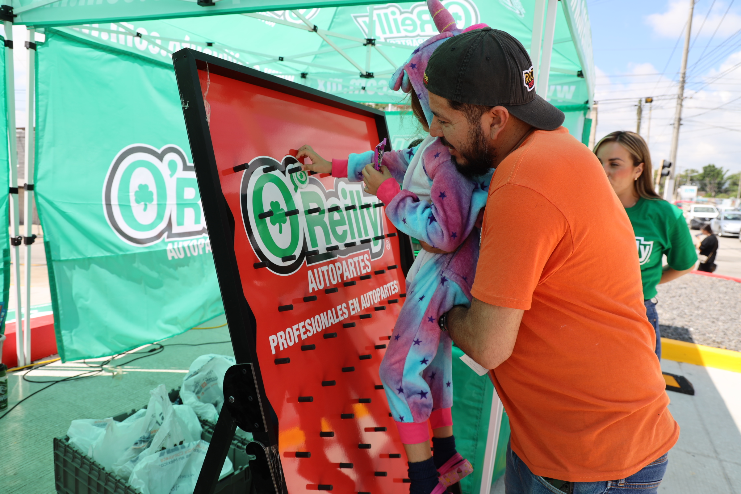 A man and little girl play a game as part of the celebration of 100 O'Reilly Auto Parts stores in Mexico.
