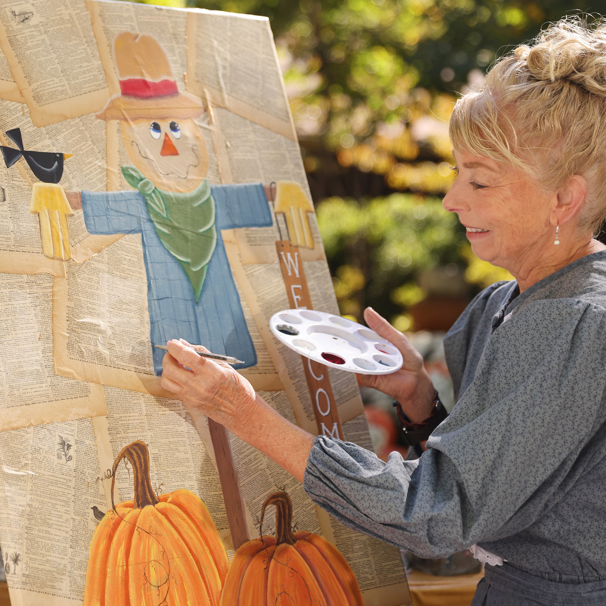 Photo courtesy: Silver Dollar City. The image shows a woman painting a scarecrow and pumpkins.
