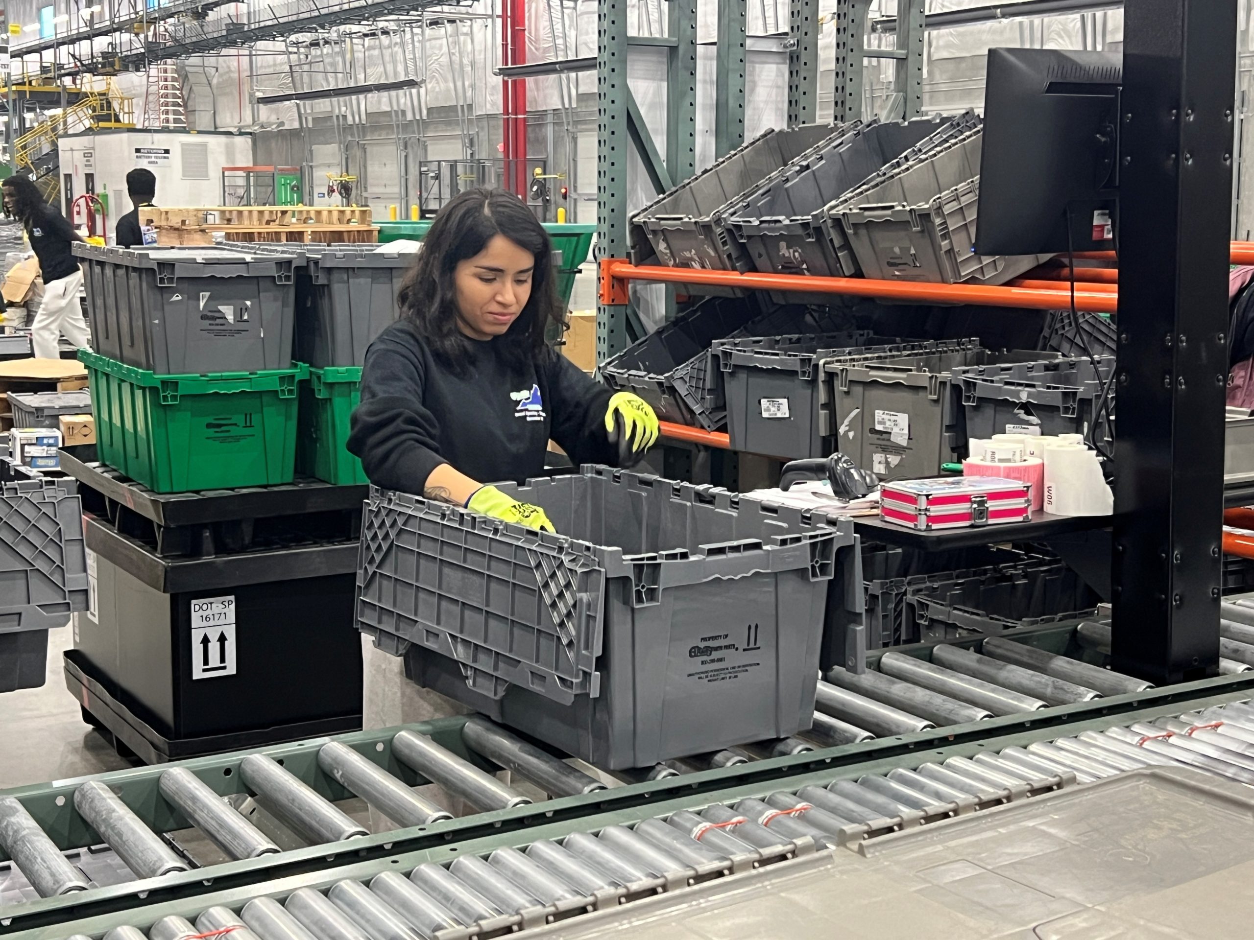 An O'Reilly team member with a black shirt loads items into a  gray tote.